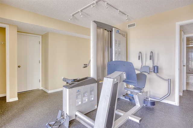 exercise area featuring a textured ceiling and rail lighting