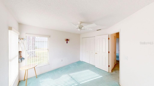 carpeted spare room with a textured ceiling and ceiling fan