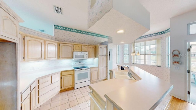 kitchen featuring light tile flooring, tasteful backsplash, light brown cabinetry, white appliances, and sink