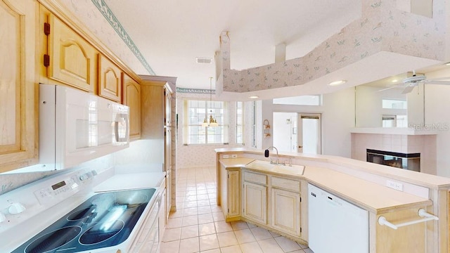 kitchen with an island with sink, white appliances, ceiling fan, sink, and a fireplace