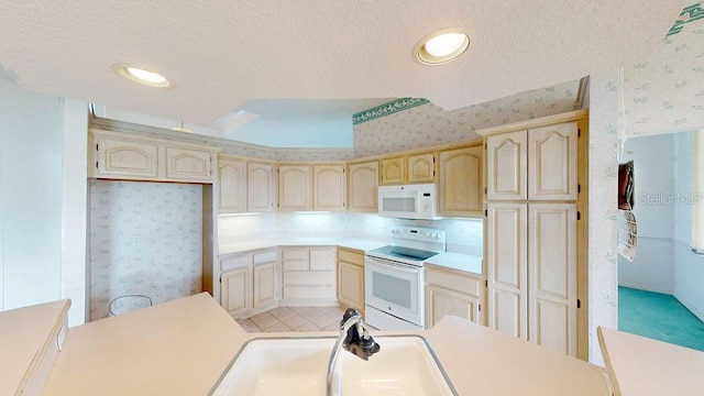 kitchen with light brown cabinets, white appliances, and a textured ceiling