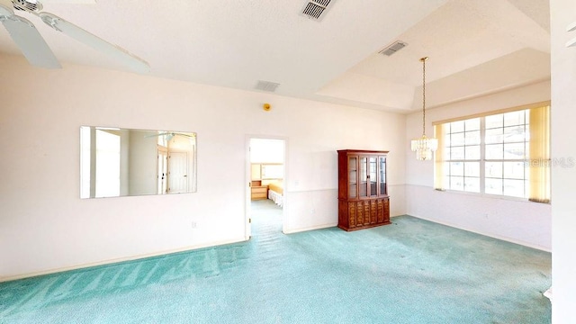 spare room featuring a raised ceiling, carpet floors, and ceiling fan with notable chandelier