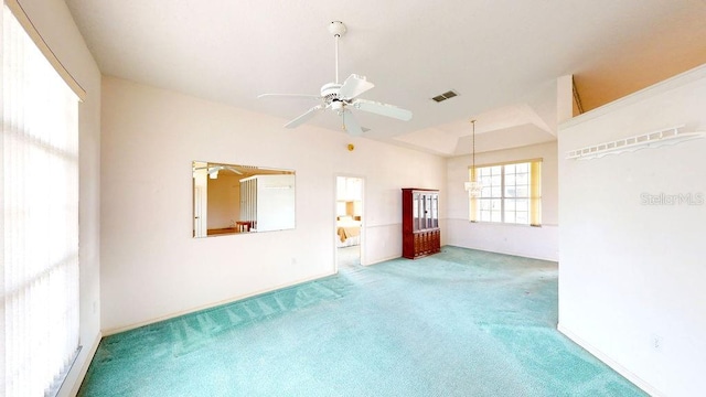 empty room featuring lofted ceiling, light colored carpet, a raised ceiling, and ceiling fan