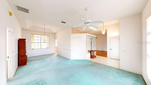 spare room featuring light carpet, ceiling fan with notable chandelier, and a raised ceiling