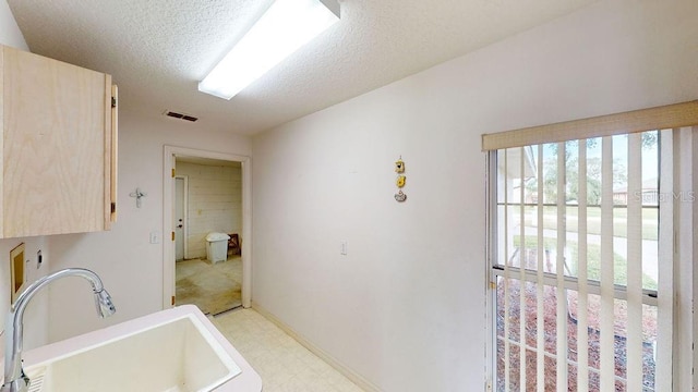 bathroom with a textured ceiling, tile floors, a bathtub, and sink