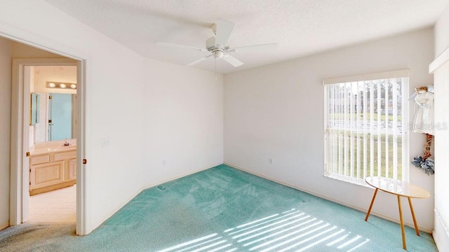 spare room with a textured ceiling, ceiling fan, a healthy amount of sunlight, and light colored carpet