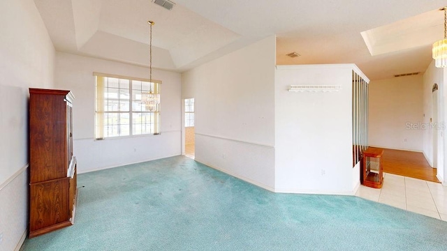 carpeted spare room with an inviting chandelier and a raised ceiling