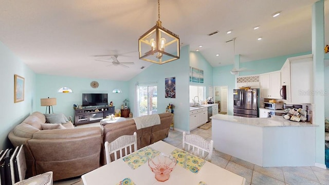 tiled dining area with lofted ceiling and ceiling fan with notable chandelier