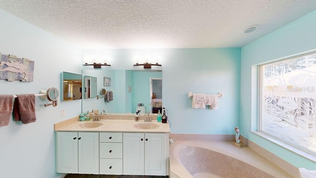 bathroom featuring a textured ceiling, a bathtub, and double vanity