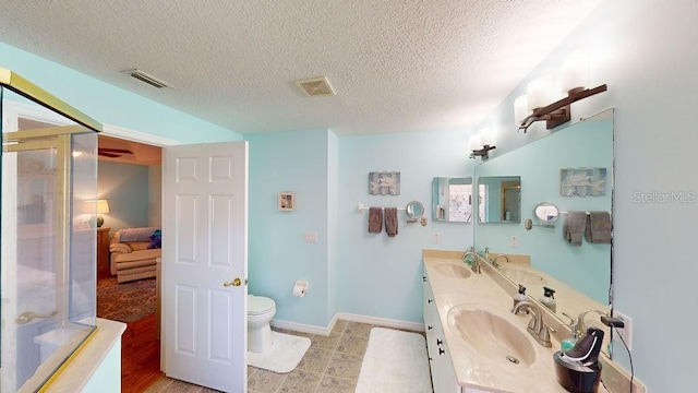 bathroom featuring toilet, hardwood / wood-style floors, dual vanity, and a textured ceiling