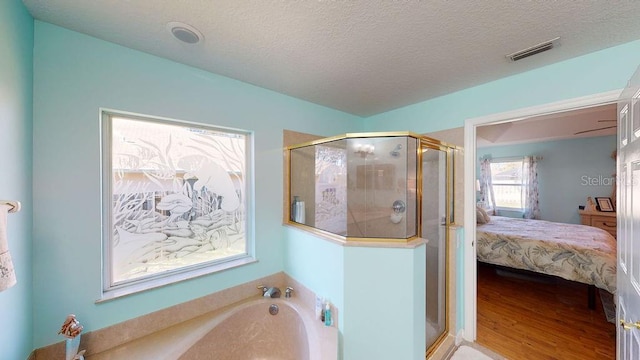 bathroom with hardwood / wood-style floors, a textured ceiling, and separate shower and tub