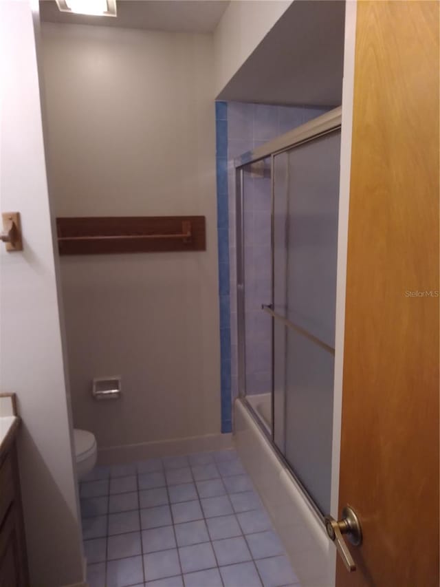 full bathroom with combined bath / shower with glass door, vanity, tile floors, and toilet