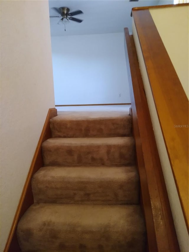 stairs featuring ceiling fan