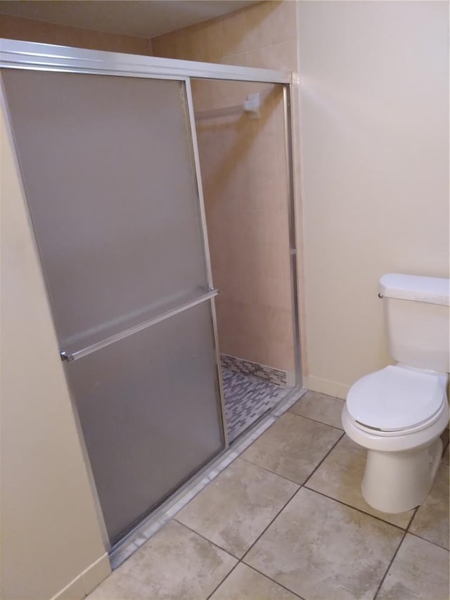 bathroom with toilet, a shower with shower door, and tile flooring