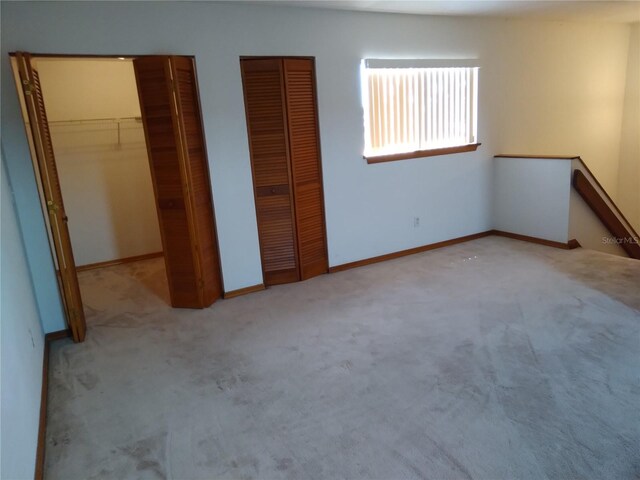 unfurnished bedroom with light carpet and two closets