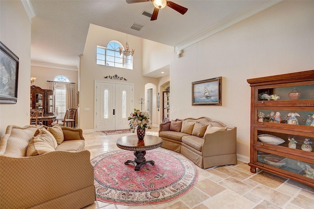 tiled living room with a high ceiling, ceiling fan with notable chandelier, and ornamental molding