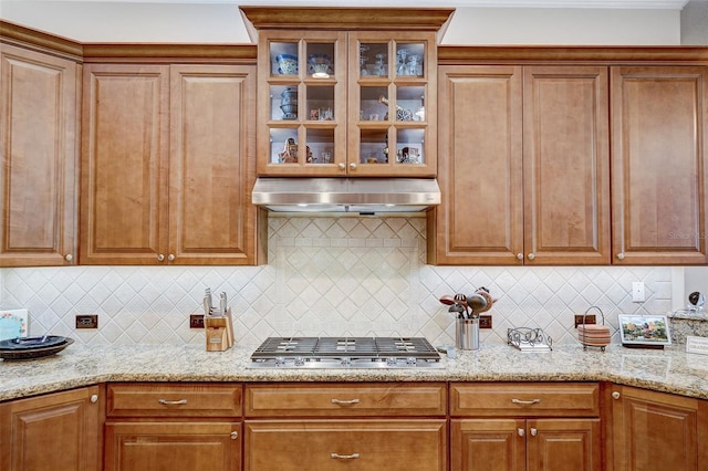 kitchen with light stone countertops, stainless steel gas cooktop, and backsplash