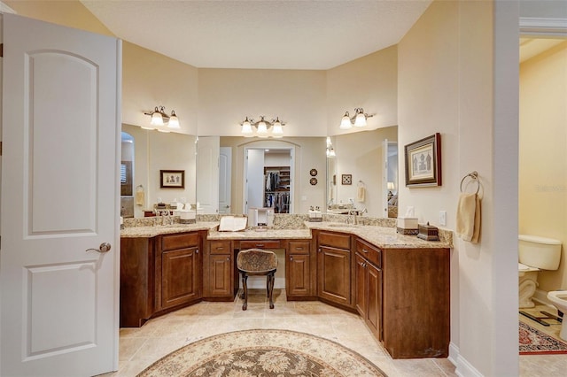 bathroom with a bidet, oversized vanity, double sink, and tile flooring