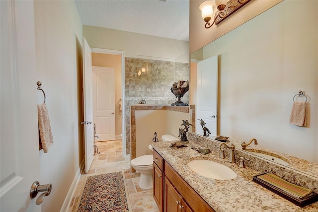 bathroom featuring toilet, a tile shower, tile flooring, a textured ceiling, and vanity