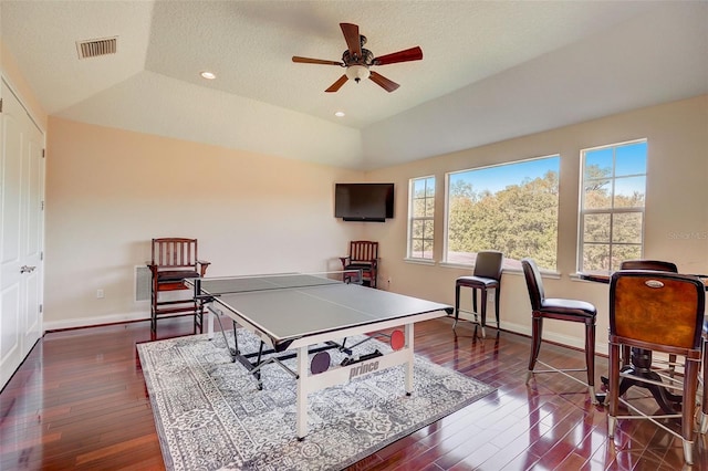 playroom with dark hardwood / wood-style flooring, a textured ceiling, ceiling fan, and a tray ceiling