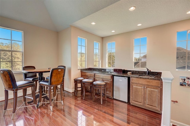 interior space with light hardwood / wood-style floors, a textured ceiling, sink, and a wealth of natural light