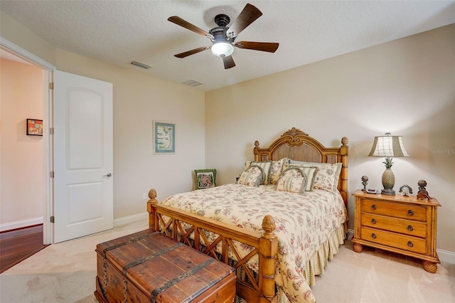 bedroom featuring a textured ceiling, ceiling fan, and light colored carpet