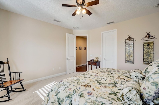 bedroom with a textured ceiling, light colored carpet, and ceiling fan