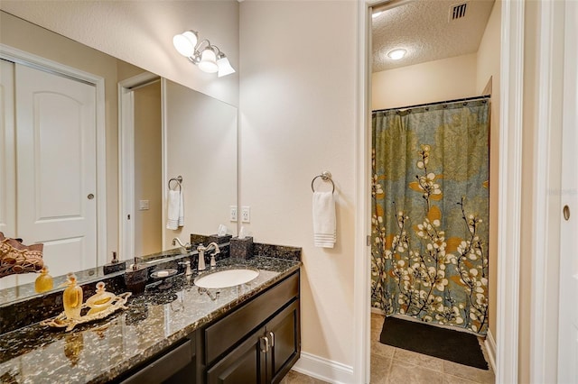 bathroom with a textured ceiling, tile floors, and large vanity