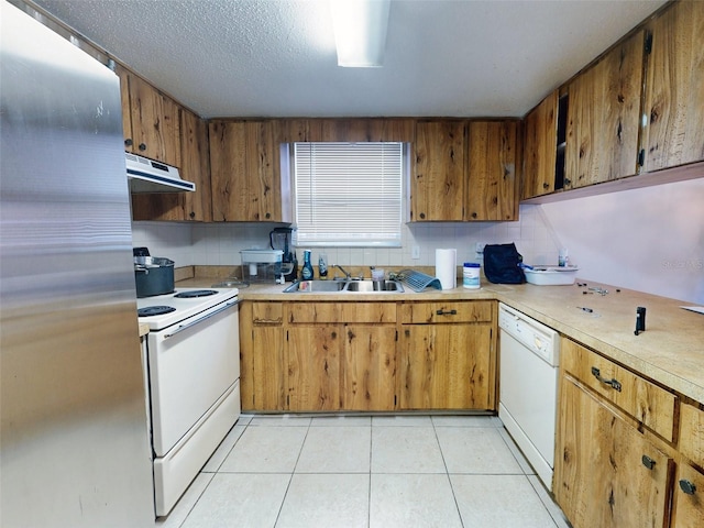 kitchen featuring white appliances, a textured ceiling, sink, and light tile floors