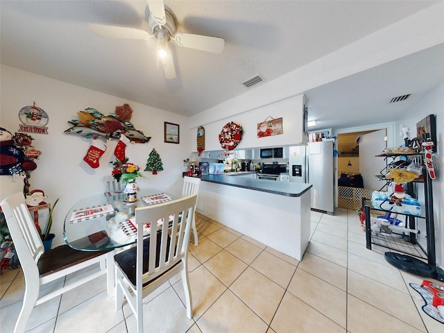 kitchen with appliances with stainless steel finishes, kitchen peninsula, ceiling fan, and light tile flooring