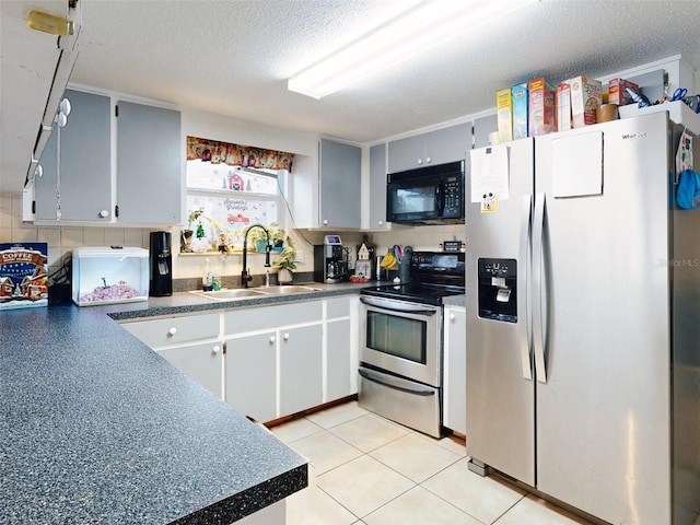 kitchen featuring stainless steel appliances, light tile flooring, a textured ceiling, tasteful backsplash, and sink