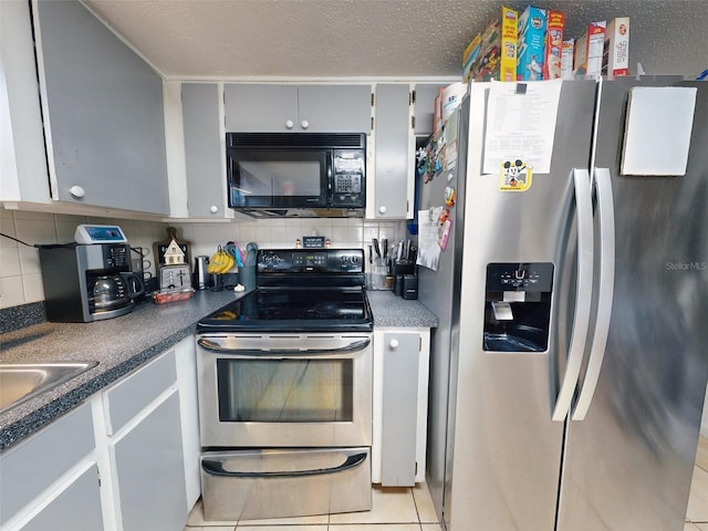 kitchen featuring tasteful backsplash, a textured ceiling, appliances with stainless steel finishes, and light tile floors