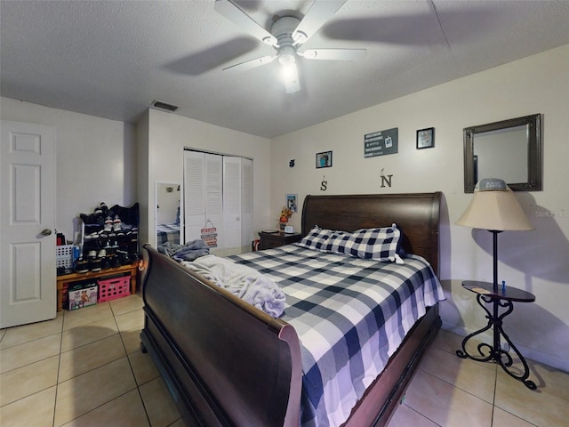 tiled bedroom with a closet, a textured ceiling, and ceiling fan