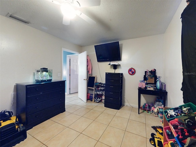 bedroom featuring light tile floors, ceiling fan, and a textured ceiling