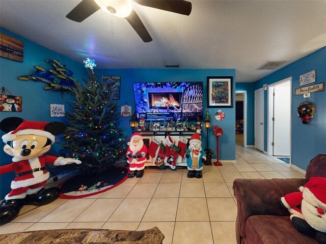 living room featuring ceiling fan, light tile floors, and a textured ceiling