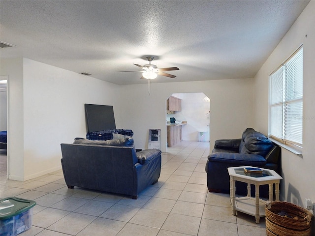 tiled living room with a textured ceiling and ceiling fan