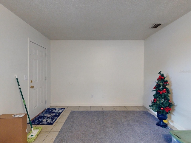 tiled empty room with a textured ceiling