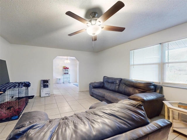 living room with a textured ceiling, ceiling fan, and light tile flooring