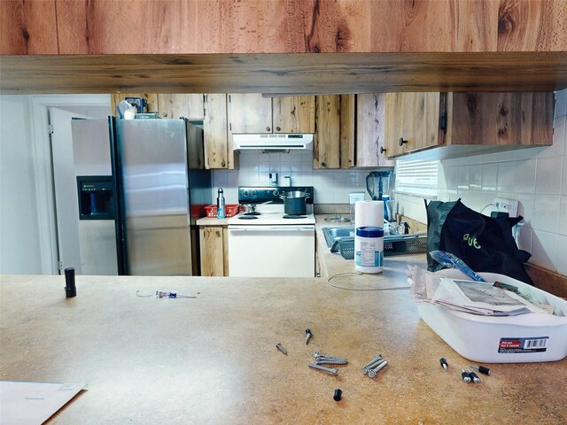 kitchen featuring electric stove, stainless steel fridge, and tasteful backsplash