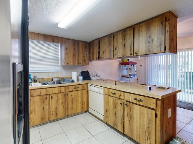 kitchen featuring kitchen peninsula, light tile flooring, and dishwasher