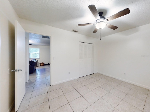 tiled spare room with ceiling fan and a textured ceiling