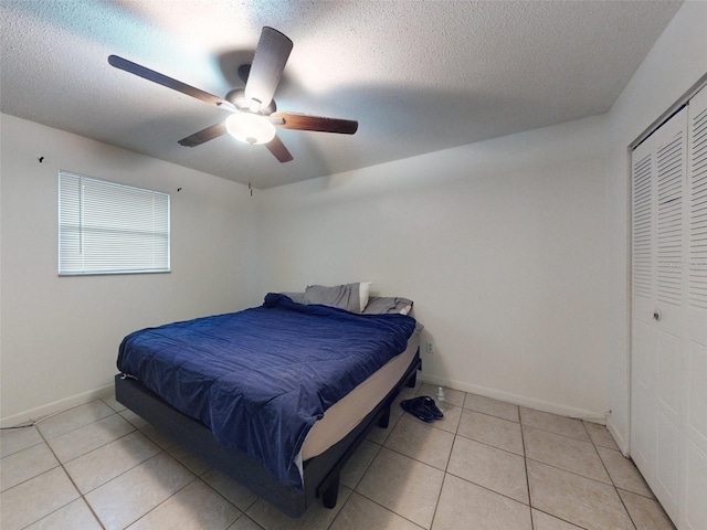 bedroom featuring light tile flooring, a closet, ceiling fan, and a textured ceiling