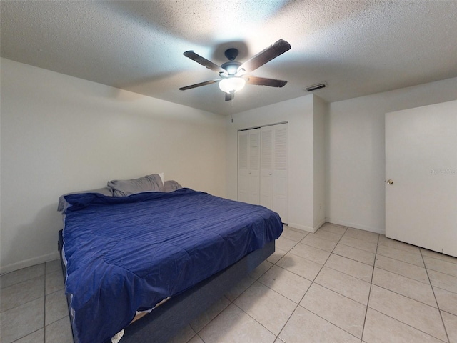 tiled bedroom with a closet, ceiling fan, and a textured ceiling