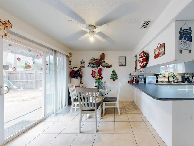 tiled dining area featuring sink, a textured ceiling, ceiling fan, and a healthy amount of sunlight