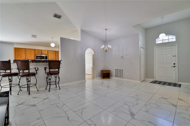 tiled foyer entrance featuring a notable chandelier and high vaulted ceiling