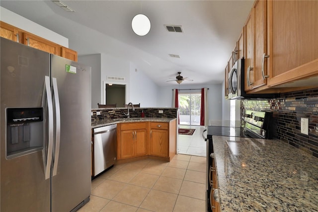 kitchen with ceiling fan, light tile floors, dark stone counters, appliances with stainless steel finishes, and tasteful backsplash