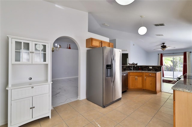 kitchen featuring pendant lighting, light tile floors, dark stone counters, stainless steel appliances, and ceiling fan with notable chandelier