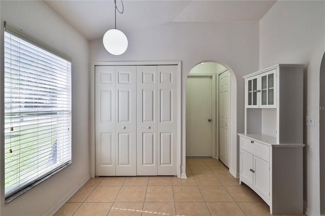 interior space with light tile floors, a closet, and vaulted ceiling