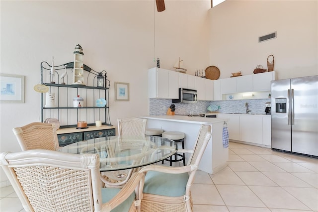 4875 S Atlantic Ave Unit E, New Smyrna Beach, FL 32169 - tiled dining space featuring sink, ceiling fan, and a towering ceiling