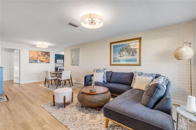 living room featuring brick wall and light wood-type flooring